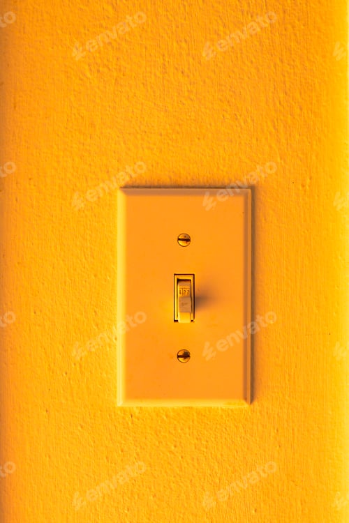 Preview: An orange wall and an orange rocker electric light switch,
