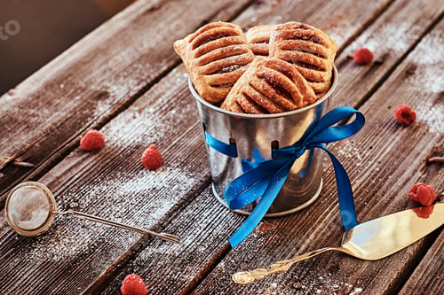 Preview: Puff pastry with jam in a bucket decorated with a blue ribbon on wooden boards with raspberries.