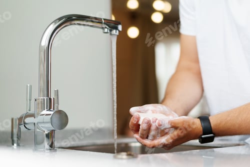 Preview: Man washing hands with soap in a sink at his home