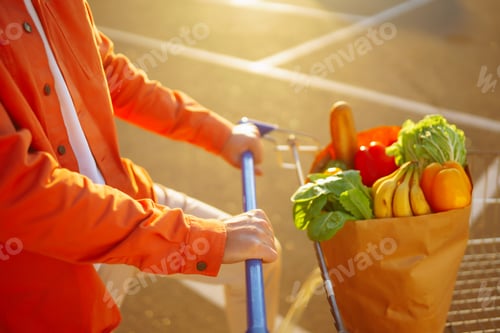 Preview: Young man with shopping bag full of vegetables near the car. Healthy lifestyle.