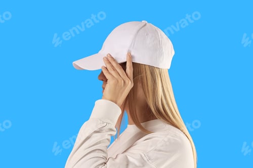 Preview: Woman adjusts her white cap while wearing a matching sweatshirt