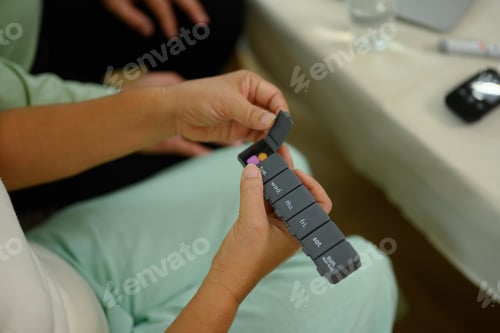 Preview: Senior woman hands taking a pill from weekly organizer. Health care, medicine and treatment concept
