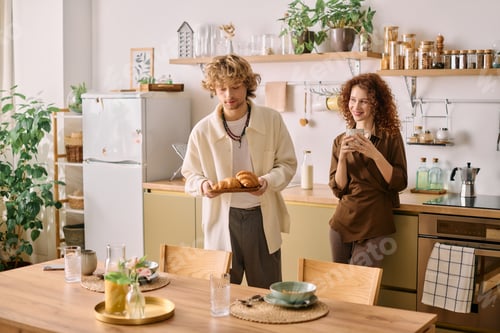 Preview: Curly young couple enjoying breakfast together in a cozy modern apartment
