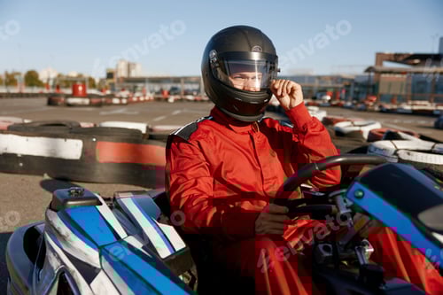 Preview: Driver taking off protective helmet while sitting at kart race car
