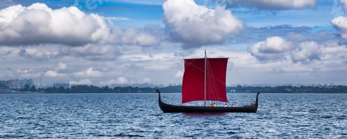 Preview: Sailboat with open scarlet sail in sea at blue sky with clouds horizon background