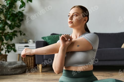 Preview: A young sporty woman in activewear stretching during her home workout routine