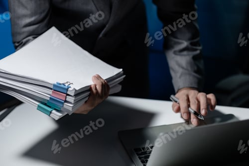 Preview: Employee checking important details of document on laptop, Documents were stacked on the desk, A bus