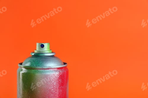 Preview: Used can of spray paint on orange background, closeup. Space for text