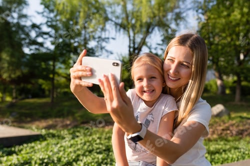 Preview: Young woman mother and daughter with long blonde hair using mobile phone