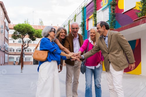 Preview: Mature friends stacking hands showing teamwork and unity