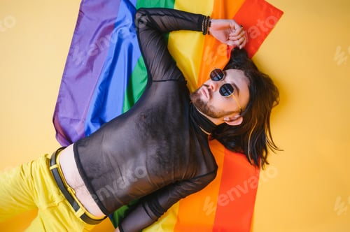 Preview: Gay man hold rainbow striped flag isolated on colored background studio portrait.