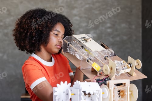 Preview: A young girl with curly hair examines a wooden mechanical model