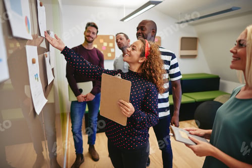 Preview: Smiling office colleagues going over paperwork on a wall