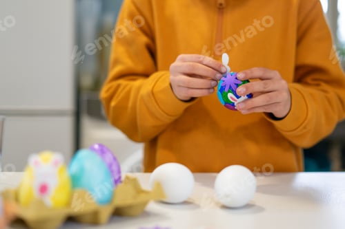 Preview: Child decorating easter eggs with colorful stickers at home