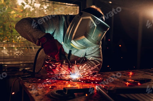 Preview: Man worker welding metal with welding machine in a factory or workshop