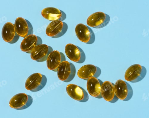 Preview: Yellow capsules with fish oil on a blue background, top view