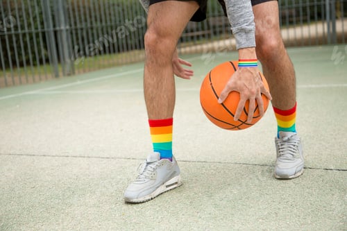 Preview: Man in sneakers and rainbow socks dribbling with a basketball ball