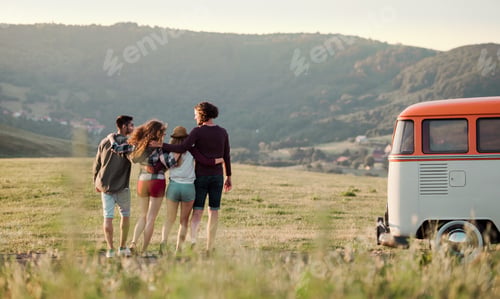 Preview: A rear view of group of young friends on a roadtrip through countryside, walking.