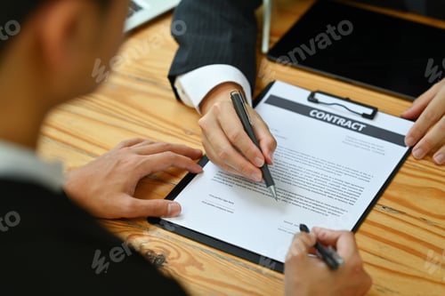 Preview: Realtor or banker pointing at contract showing male client to signature.