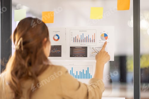Preview: Young Business Asian woman using sticky notes and graph chart in glass wall analyzing business