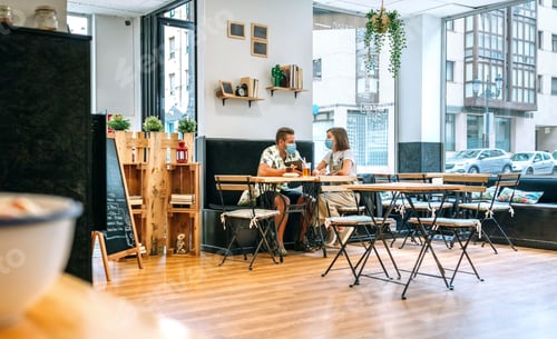 Preview: Couple with face mask having drinks in a cafe