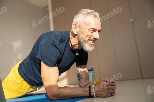 Preview: Athletic male doing a plank on a blue cover