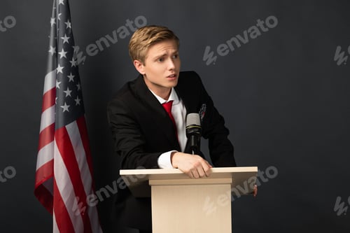 Preview: emotional man on tribune with american flag on black background