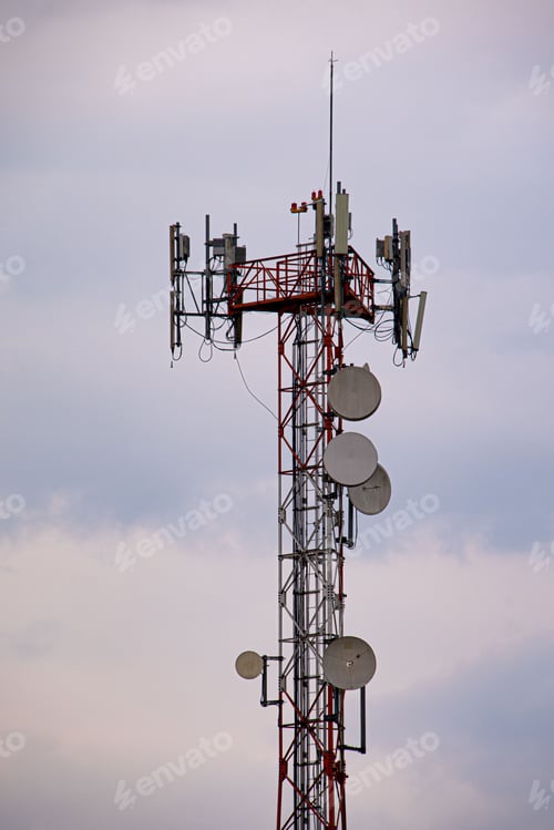 Preview: Modern telecommunication tower against cloudy sky, vertical shot