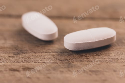 Preview: Closeup shot of white pills isolated on wooden background