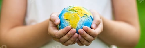 Preview: Little girl holding small planet in hands against spring or summer green background. Horizontal