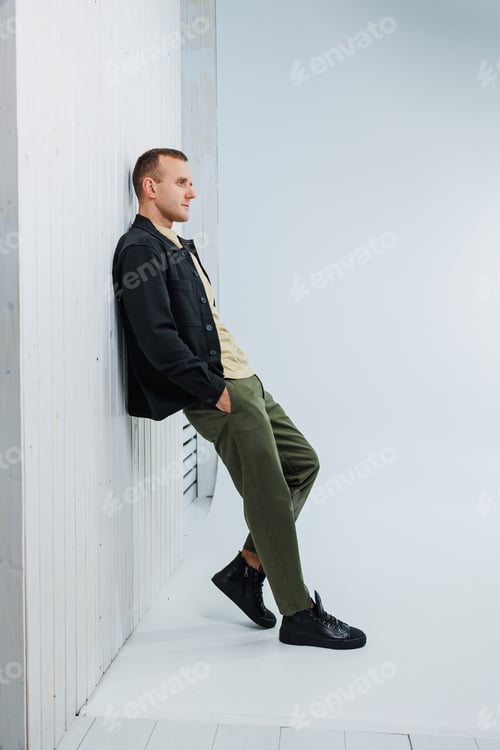 Preview: A young handsome man in casual clothes poses on a white background in the studio