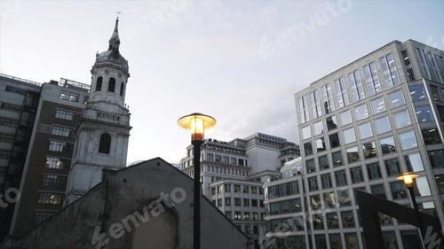 Preview: Close-up of yellow street lights in the center of London near the modern glass skyscrapers against