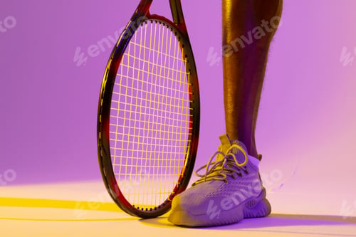 Preview: Image of leg of african american male tennis player in violet and yellow neon lighting