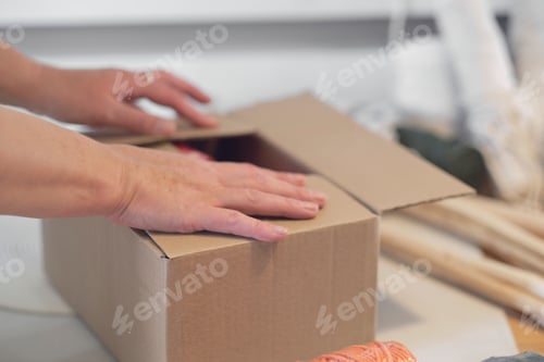 Preview: woman entrepreneur packs a handmade product in a cardboard box