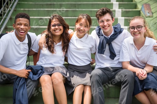Preview: Group of multinational students in uniform sitting together smiling