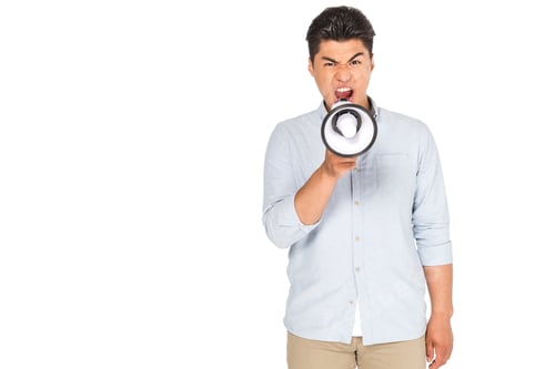 Preview: angry asian man screaming into megaphone while looking at camera isolated on white