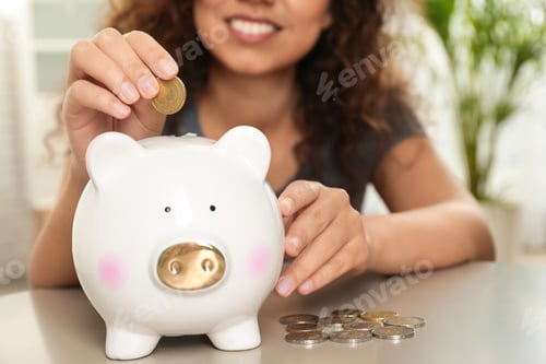 Preview: Happy woman putting coin into piggy bank at table, closeup