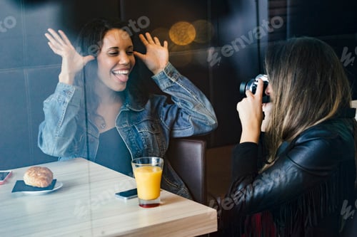 Preview: two female caucasian and african american friends having a coffee and taking picture