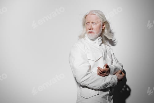 Preview: elderly man with long white hair in a white jacket, standing against a plain gray background