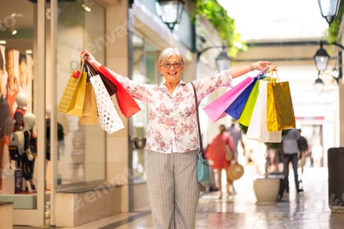 Preview: Shopping day for attractive smiling senior woman enjoying purchase holding many shopping bags