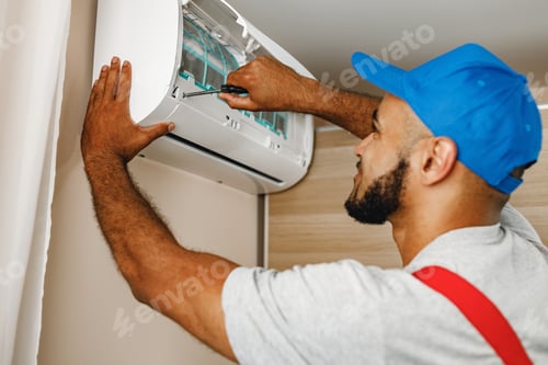 Technician Repairing Air Conditioner Unit in Home