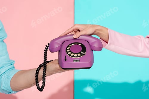 Preview: cropped view of man and woman holding purple vintage telephone on pink and blue background