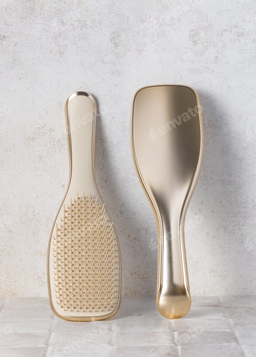 Preview: Two golden hairbrushes resting on a marble surface