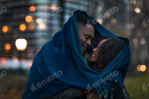 Preview: Romantic couple wrapped in blanket in city at night
