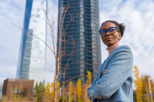 Preview: Portrait of black ethnic businesswoman or executive wearing glasses standing in business park