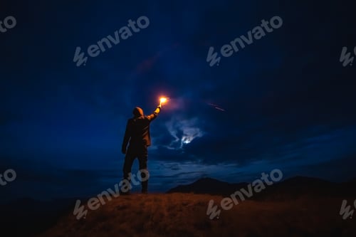 Preview: The male with a firework stick standing on a mountain. evening night time.