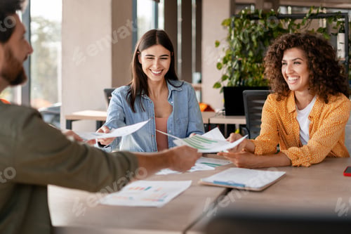 Preview: Happy business team exchanging documents during meeting