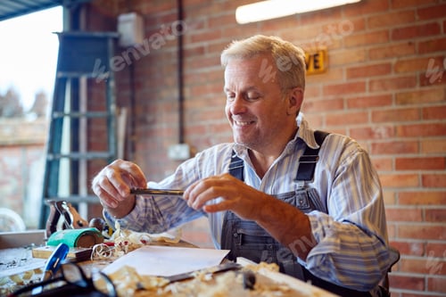 Preview: Mature Male Carpenter In Garage Workshop Taking Photo Of Design On Mobile Phone