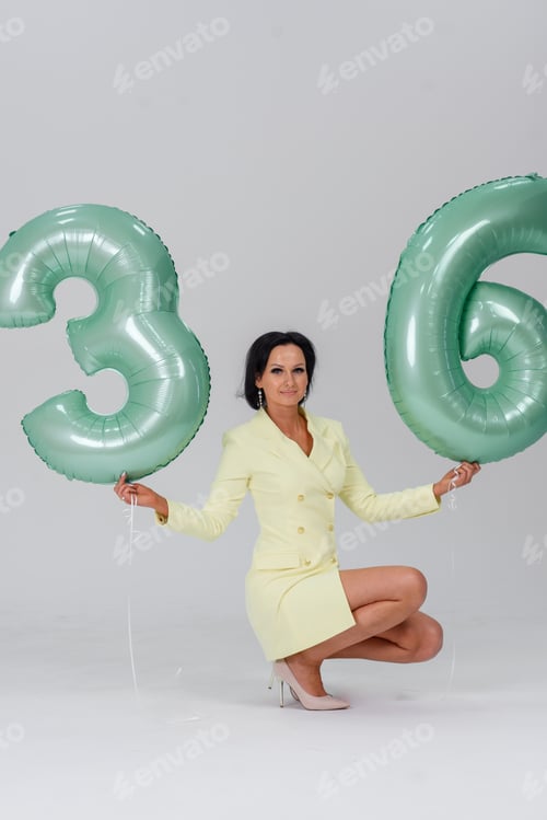 Preview: girl on a white background in a yellow dress green numbers 36 birthday balloons. holiday concept