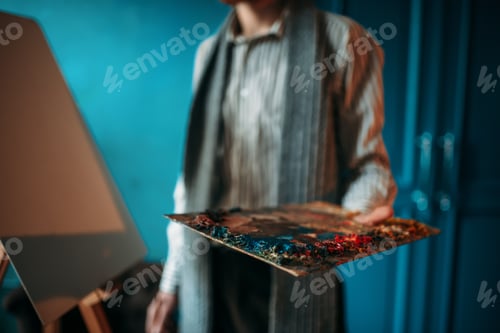 Preview: Male painter hand holds palette against the easel